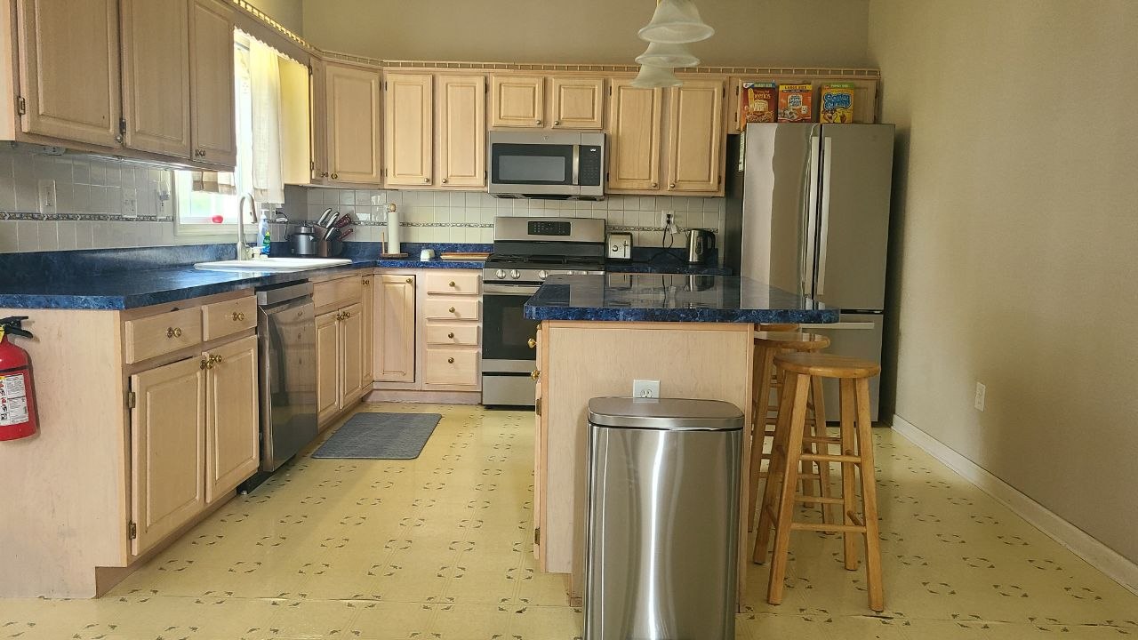Kitchen with island, wood cabinetry, and stainless-steel appliances